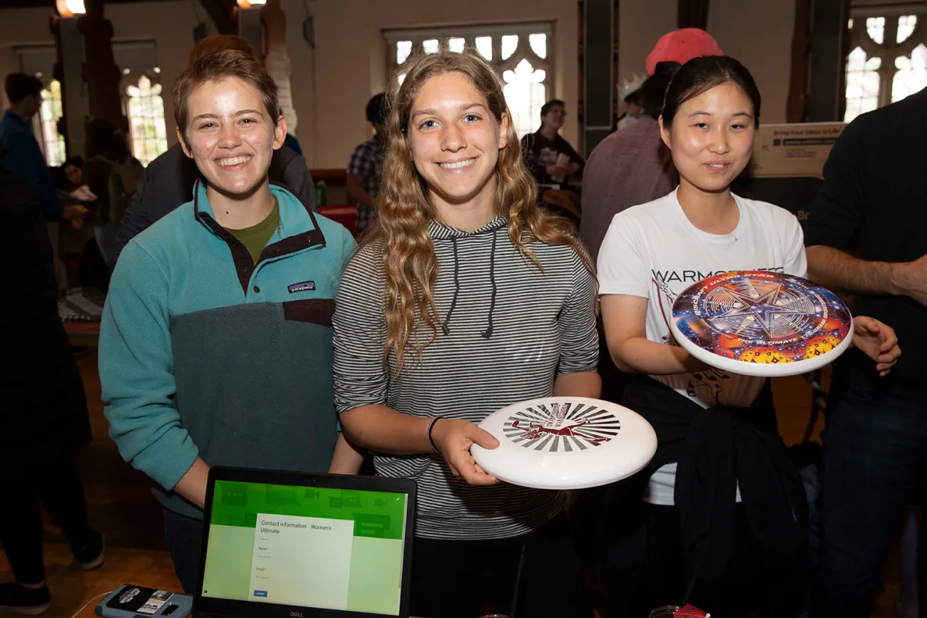 Three students hold frisbees during activity fair