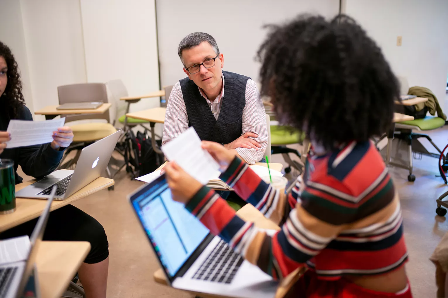 Professor talks to student on laptop