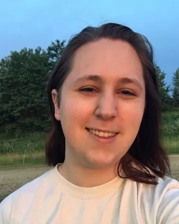 Picture of Mattie Schaefer, a nonbinary individual with shoulder-length brown hair.