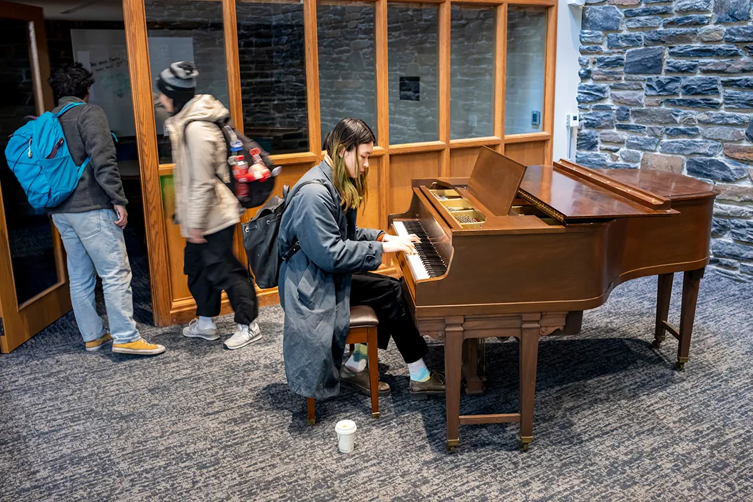 Student plays piano in Sharples commons