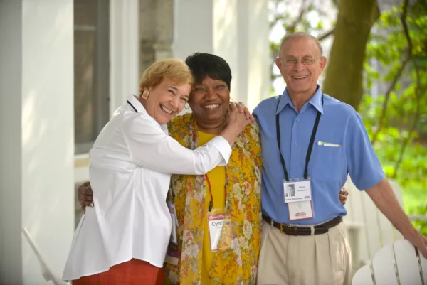3 Alumni hugging and celebrating during an event